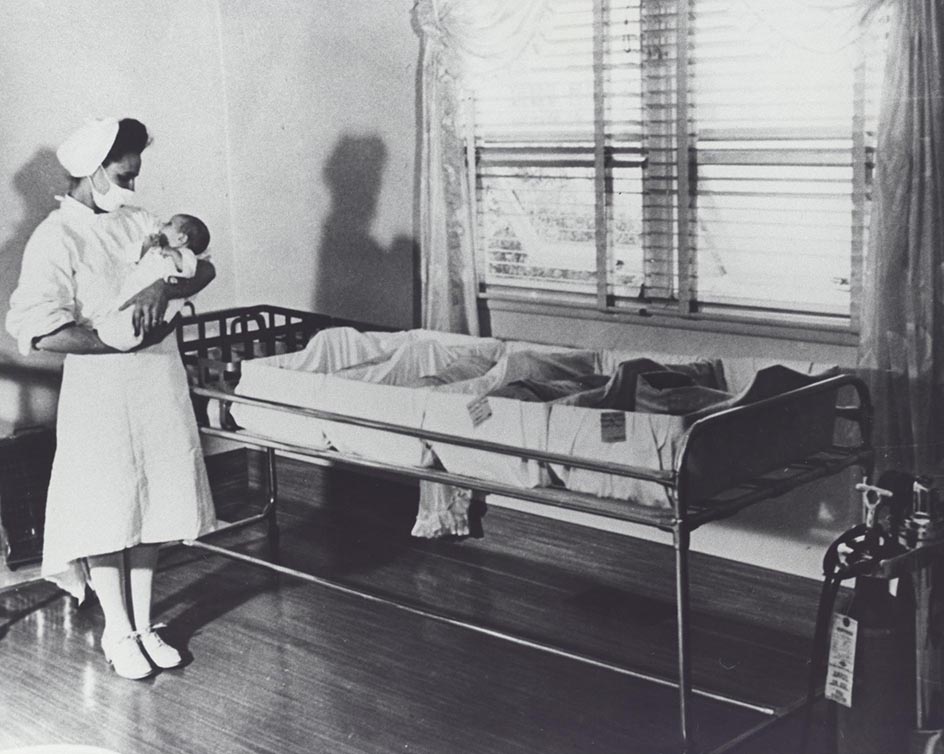 Black and white photo of a nurse holding a baby
