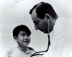 1970s photo of Permanente physician Sam Packer examines young patient.