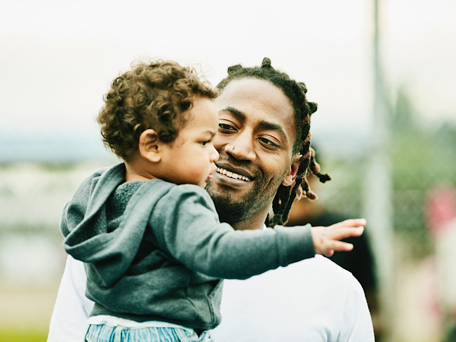 smiling father holding his toddler son