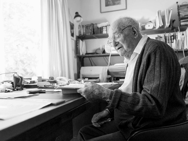 A senior man, Morris F. Collen MD, working at his desk. 