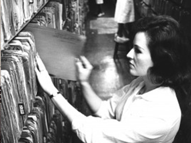 Woman handling paper files on filing rack 