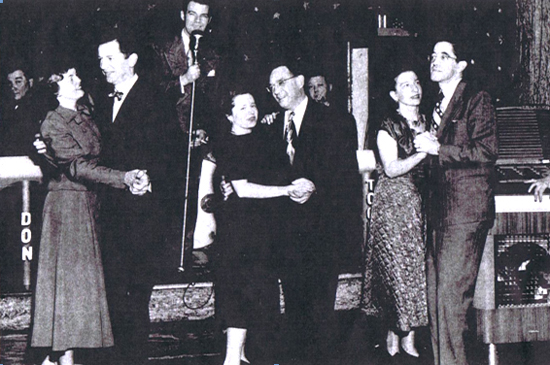 Black  and white photo of three couples partner dancing dressed in 1940s attire