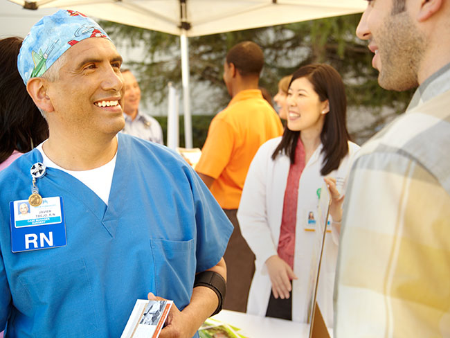 Nurse and member speak under a tent