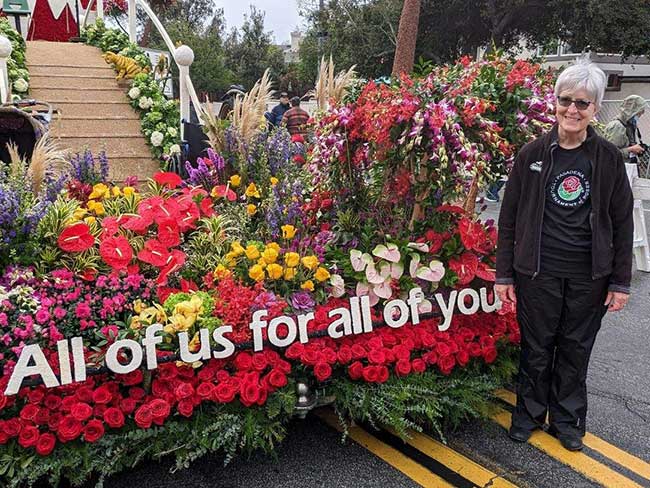 Lynn Replinger stands in front of the KP 'All of us for all of you' Rose Parade float