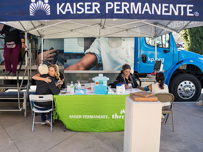 Health care workers providing care for members in front a Kaiser Permanente mobile unit