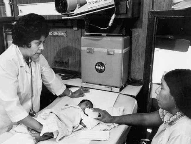 Woman doctor examining Papago baby while mother feeds with baby bottle