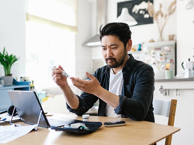 Asian man checking his blood sugar at home