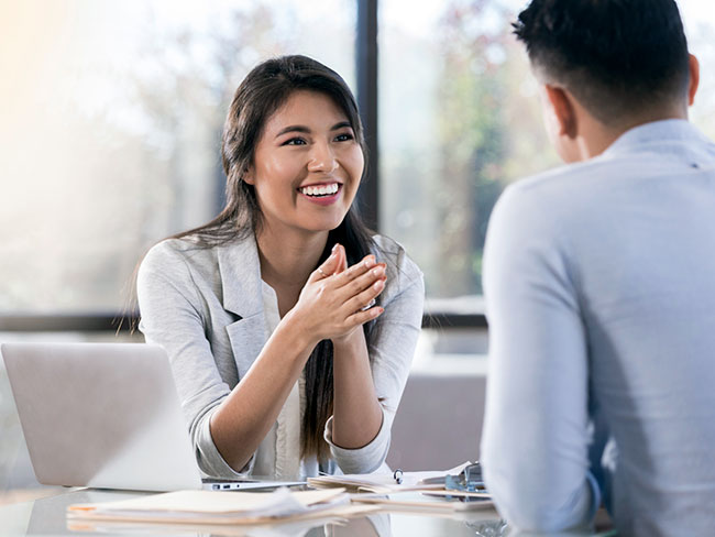 A woman smiling while talking to a business collegue