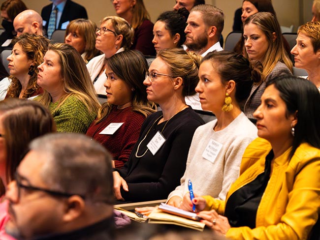 Crowd at conference, listening intently.