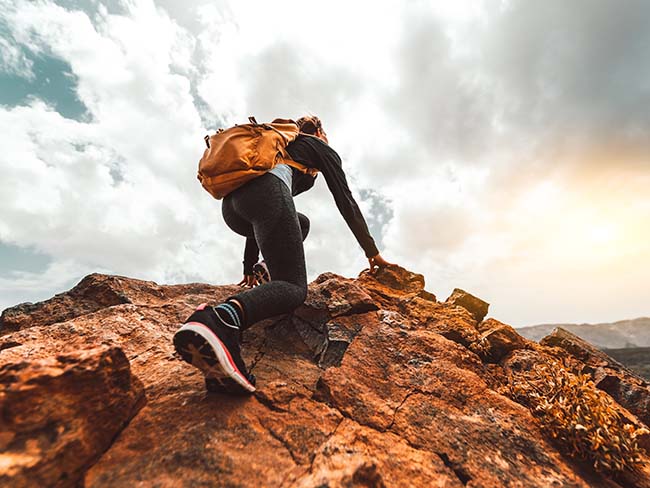 Success woman hiker hiking on sunrise mountain peak - Young woman with backpack rise to the mountain top. Discovery Travel Destination Concept