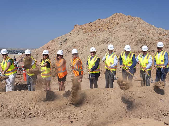 group of people at construction site using shovels to move dirt