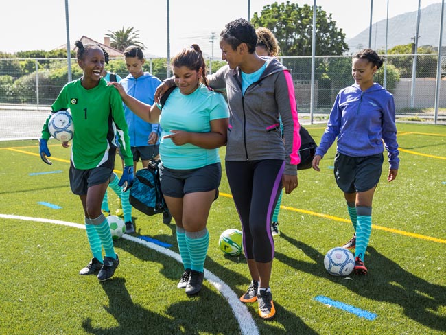 group of teenagers on a soccer field with their coach