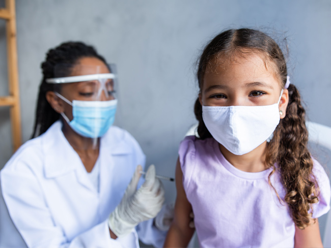 medical worker administering vaccine to young girl