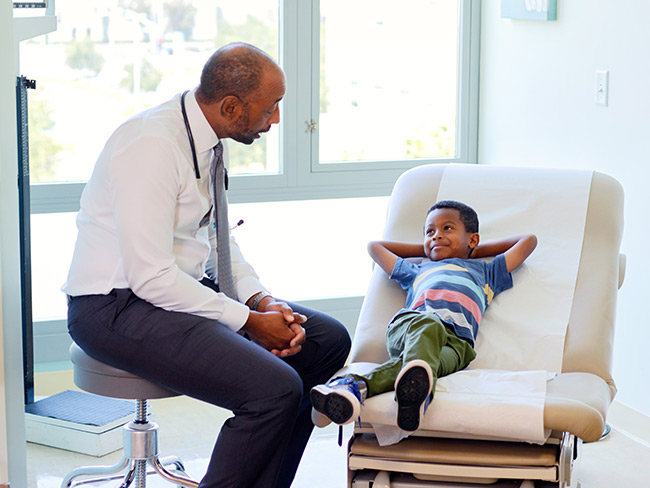 Doctor talking to a boy relaxing on an exam table