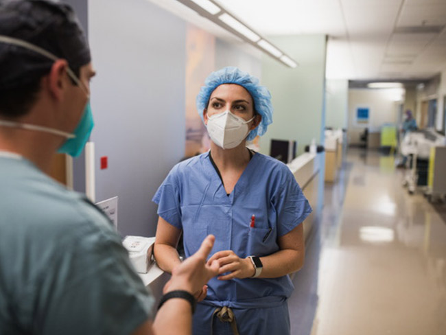 Female health care worker talking with male health care worker in a hallway