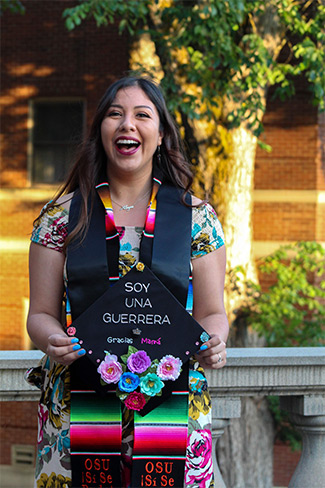 Woman standing in front brick wall after graduating