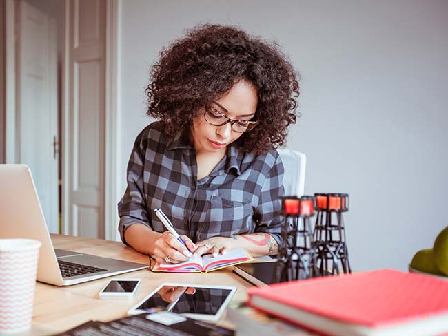 Woman working in home office taking notes.