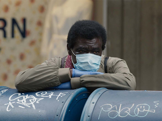 Homeless man wearing mask and gloves