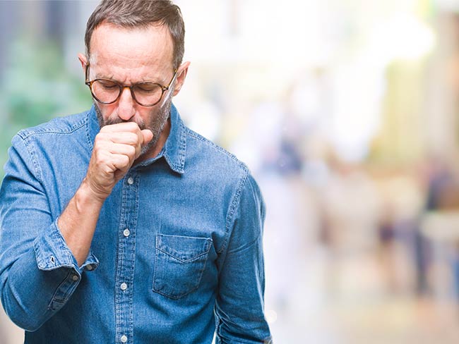 A man coughing into his fist. 