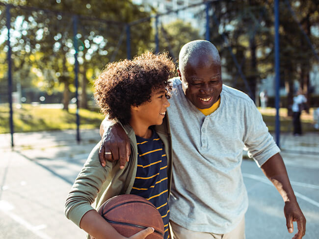 young man with older man on basketball court smiling and hugging 