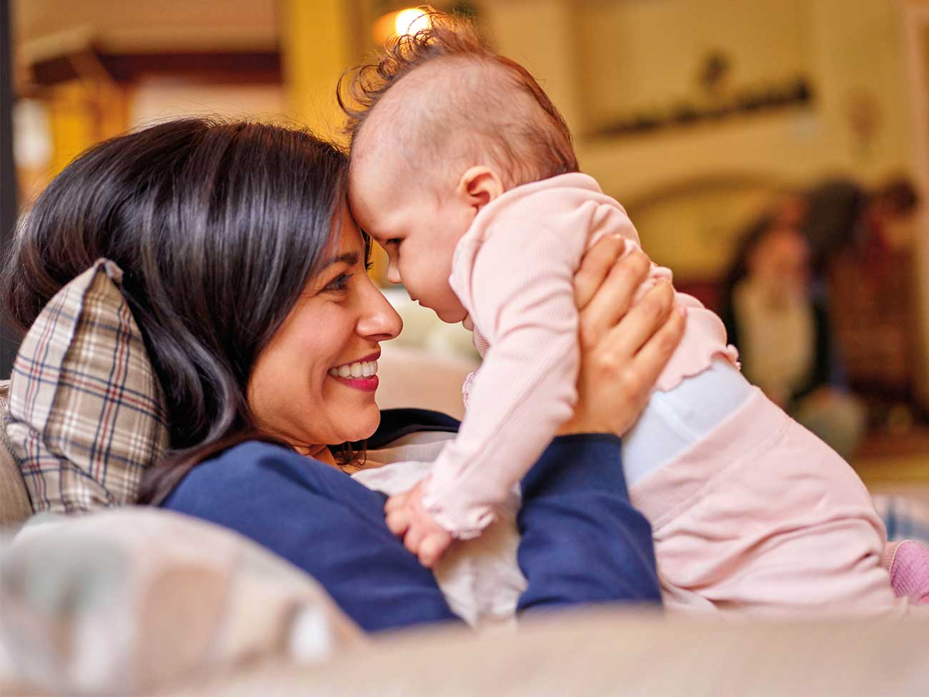 Mother smiling and holding baby on a couch