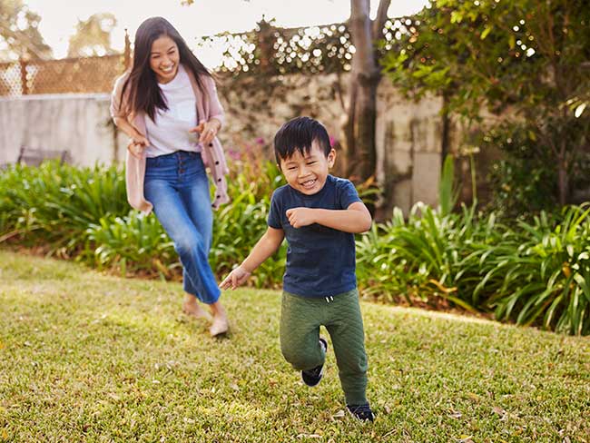 A happy mom and sun are running in their backyard