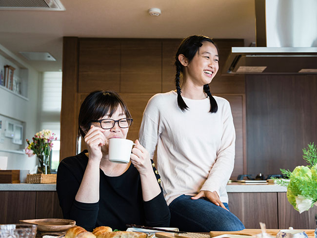 Asian mother and daughter relaxed while having lunch together at their dining room table.