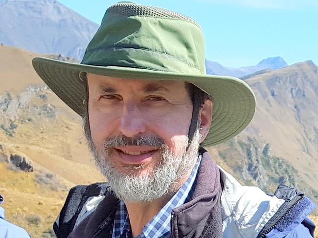 Kaiser Permanente member Harold Newman in a green brimmed hat  hiking in the mountains.