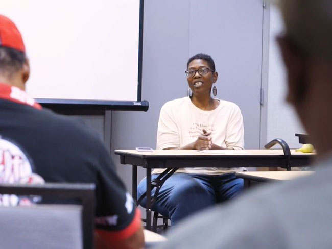 Waleisah Wilson seated at desk in front of class.