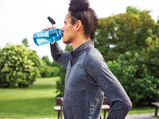 Man drinking water outside on a hot day