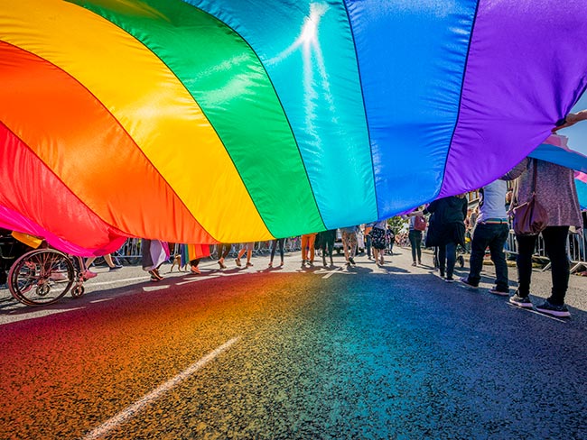 Giant Pride flag being held by numerous people