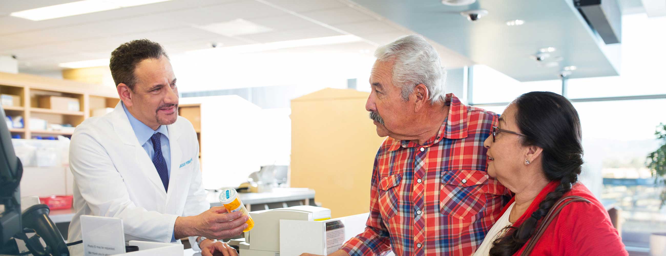 Husband and wife speaking to a pharmacist about a prescription. 