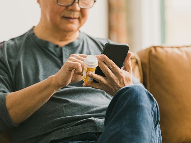 Man holding prescription bottle and phone