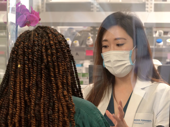 woman speaking to pharmacist behind window