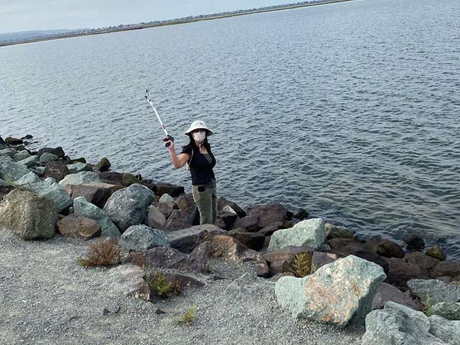 Vi Nguyen, MD, picking up trash on the beach in San Diego.