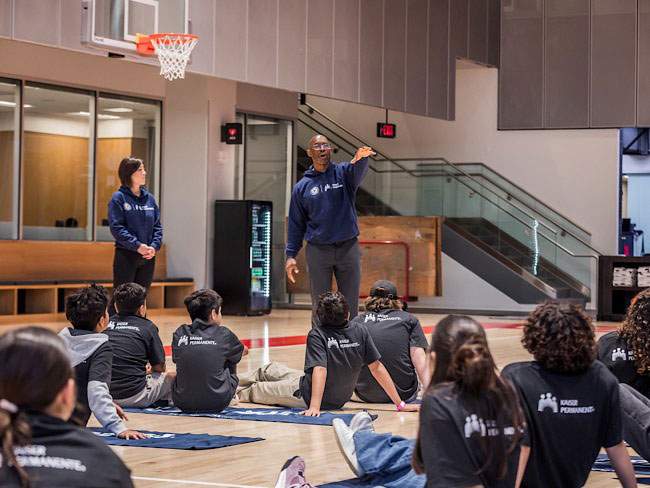 2 coaches talking to teens sitting on yoga mats