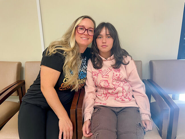 mother and daughter seated inside a patient waiting room