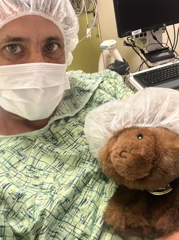 Christopher Hogan in hospital bed with his stuffed bear