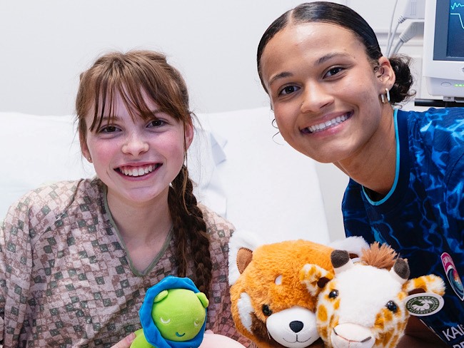 girl in hospital bed smiling with female soccer player