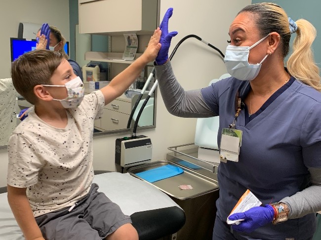 Nurse and child give high fives after he gets the flu vaccine. 