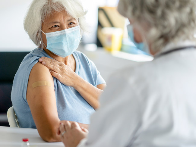 Senior women wearing face mask getting vaccination