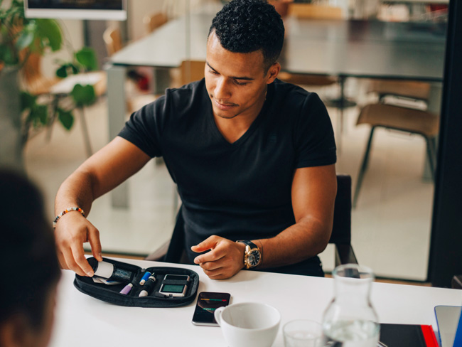 man seated at table preparing to administer his own blood test