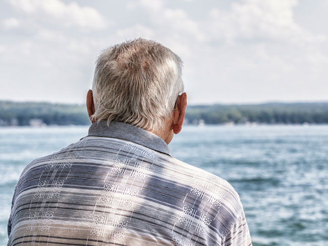 Senior man rear view looking at a lake.