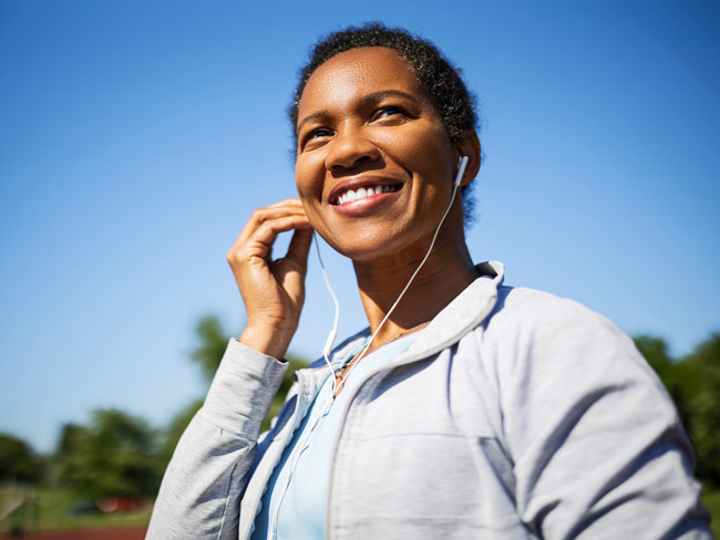 smiling woman wearing headphones in a park