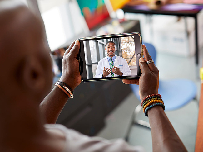 man holding tablet computer with doctor on screen