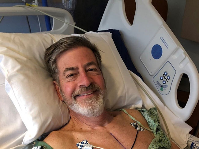 smiling man lying on hospital bed