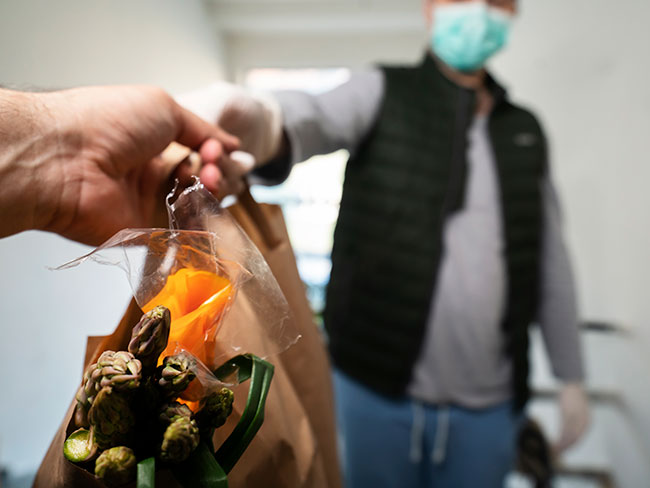 Young man as volunteer wearing a face mask, delivering groceries.