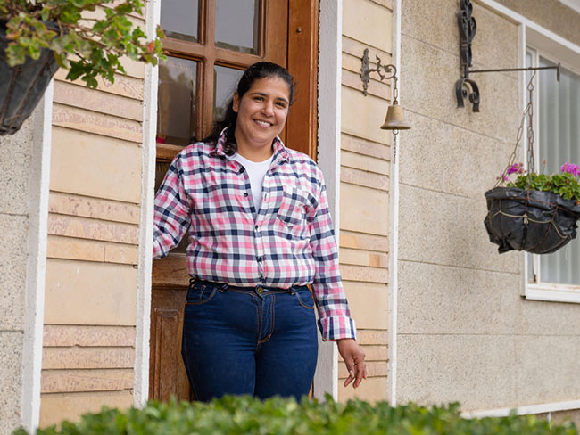 smiling woman standing in front of doorway of house