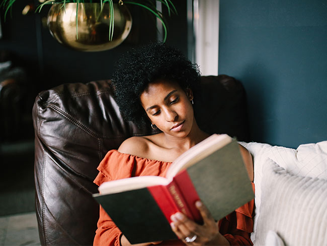 Woman reading in a chair in her home.