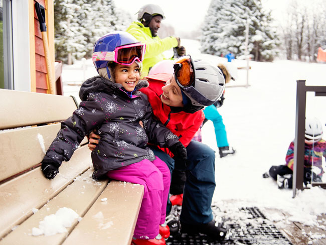 family dressed in ski outfits outdoors in the snow